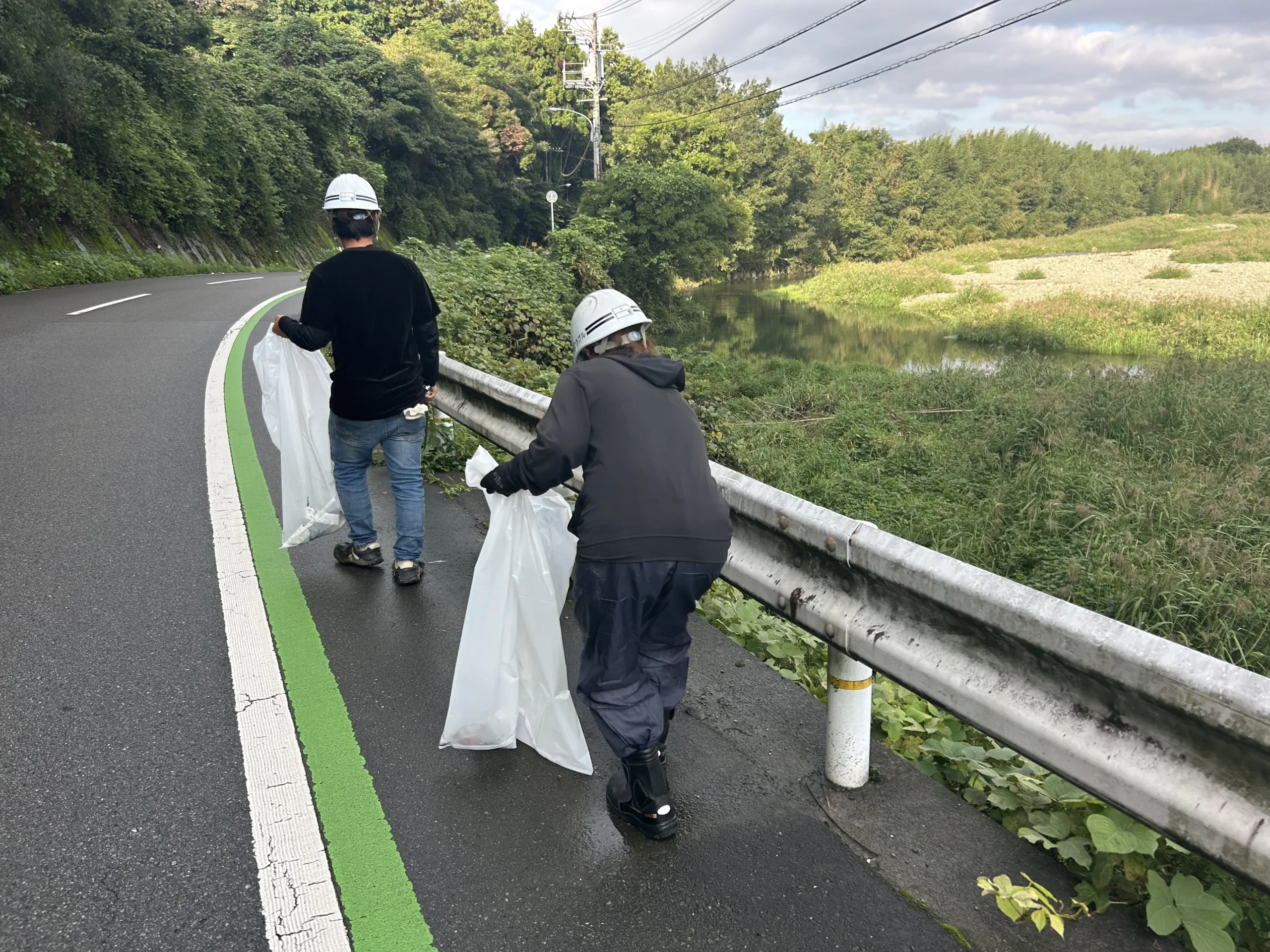 川沿いの道路でごみを拾いながら歩く社員たち