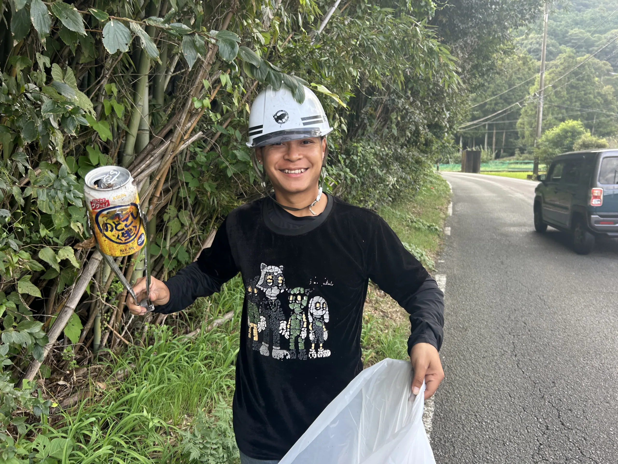 道路清掃で拾った空き缶をトングで回収する社員